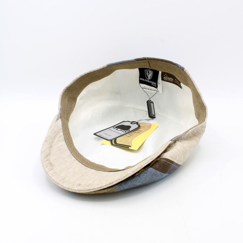 A vintage-style newsboy cap shown from the inside, featuring a beige and brown patterned fabric exterior and a white interior lining with attached tags.