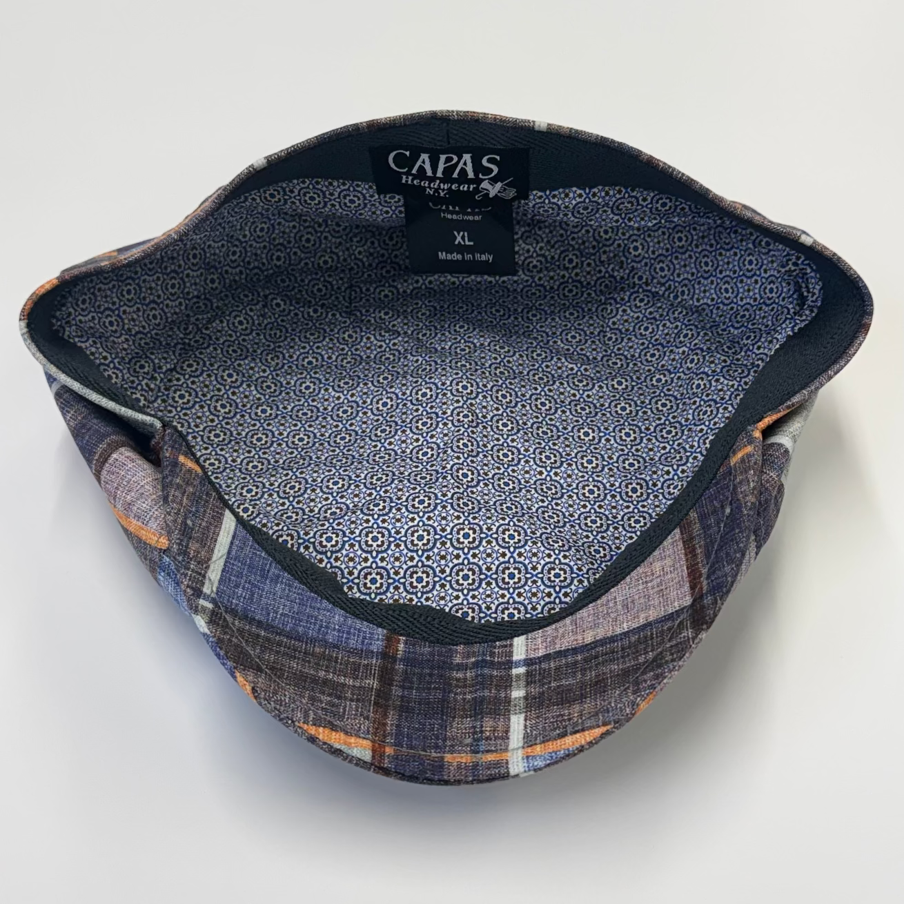 Fabric sample with plaid pattern and 'CAPAS' branding on a white background
