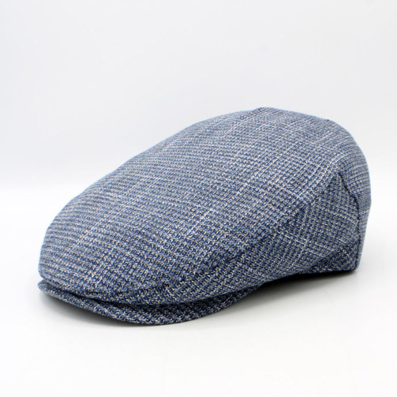 A blue and gray textured flat cap, also known as a newsboy cap, shown from a three-quarters angle on a white studio background.