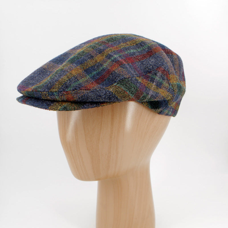 A multicolor plaid flat cap displayed on a light wood mannequin head against a white studio background.
