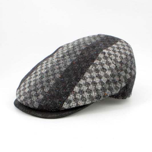 A flat cap in a black and gray houndstooth pattern with a solid black side panel, photographed on a clean white background.