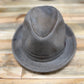 A distressed gray felt fedora hat resting on a rustic wooden plank surface.