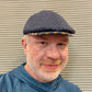 Navy Ionio flat cap worn with ear flaps tucked in