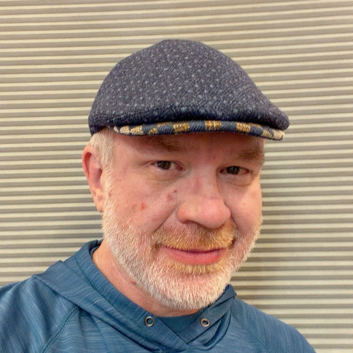 Navy Ionio flat cap worn with ear flaps tucked in