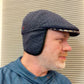 Navy Ionio flat cap worn with ear flaps down