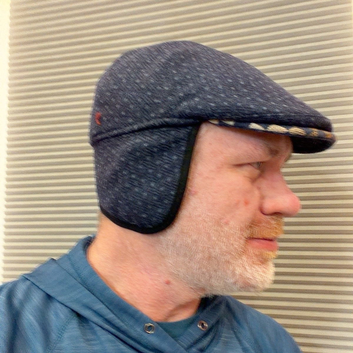 Navy Ionio flat cap worn with ear flaps down