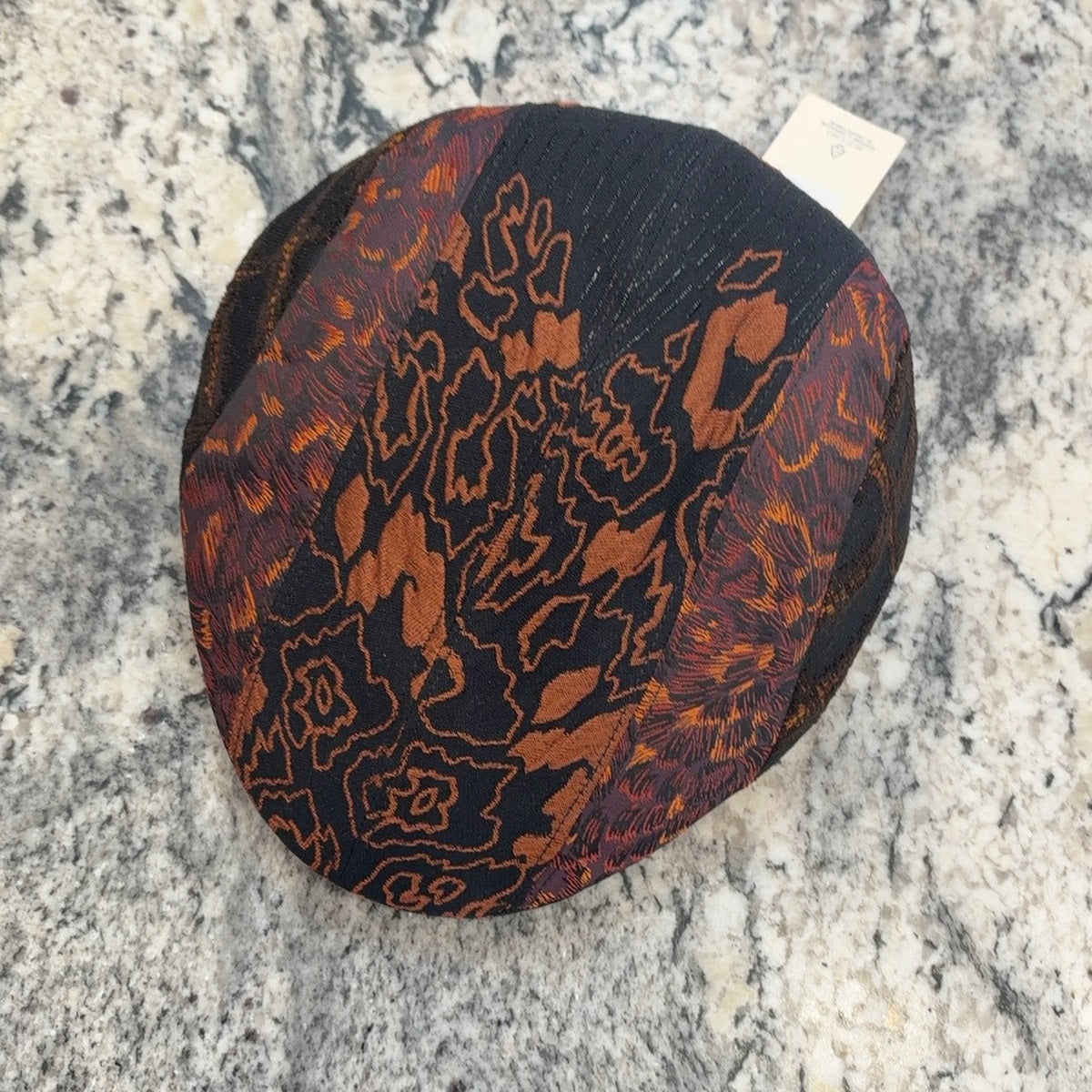 Top view of John 52062 black rust and orange patchwork flat cap