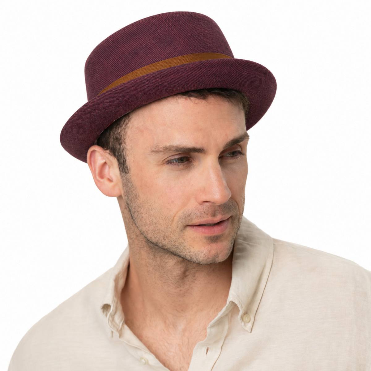 A man wearing a purple woven pork pie hat with a tan band, paired with a light beige linen shirt, photographed against a solid white background.