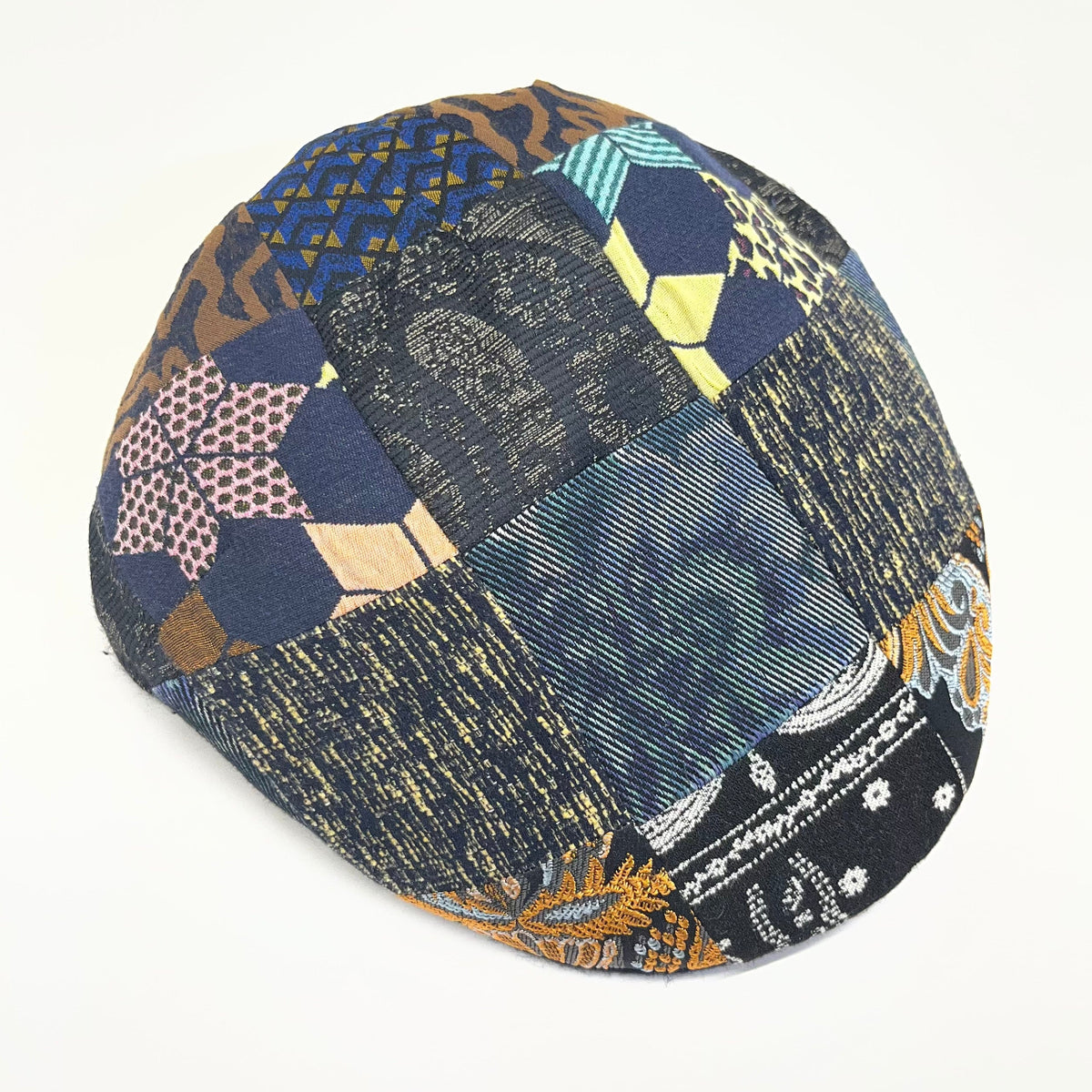 Alfonso D'Este Tirreno flat cap with multicolor geometric, striped and paisley-style patchwork in navy, yellow, tan and pale green