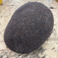 A classic flat cap in a brown and gray herringbone tweed pattern, resting on a speckled stone countertop.