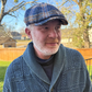 Man wearing a blue checkered cap and patterned jacket outdoors