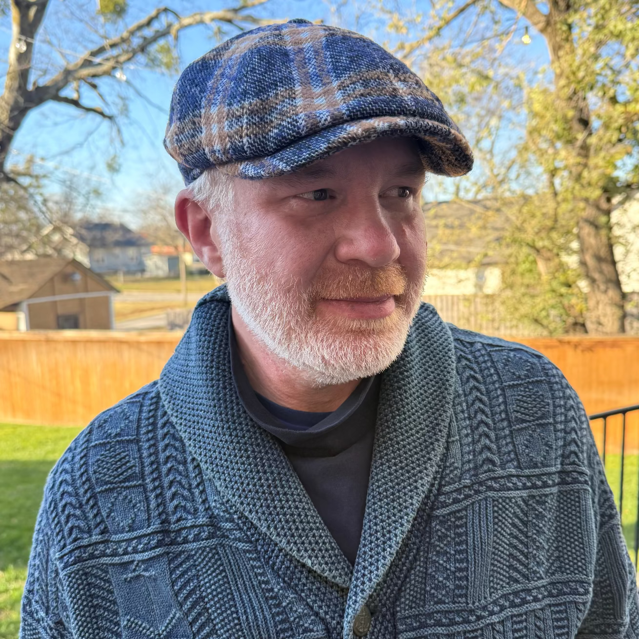 Man wearing a blue checkered cap and patterned jacket outdoors