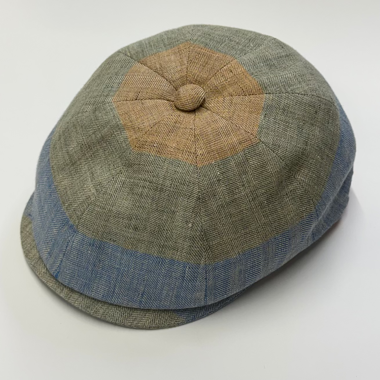 Green and brown checkered flat cap on a white background