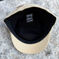 A beige baseball cap viewed from above, showing a black interior lining and a small black brand patch that reads 'Buckeye Park'.