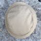 A beige fabric hat or cap laid flat on a gray stone surface, photographed from above.