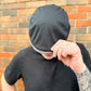 Person wearing a black beanie in front of a brick wall