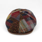 A multicolor patchwork plaid flat cap hat with a brown leather visor and a brown button on top, photographed on a clean white background.