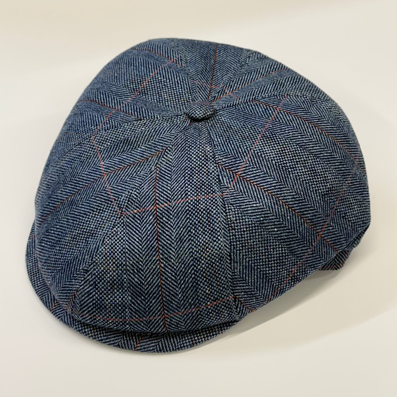 Blue checkered flat cap on a light beige background