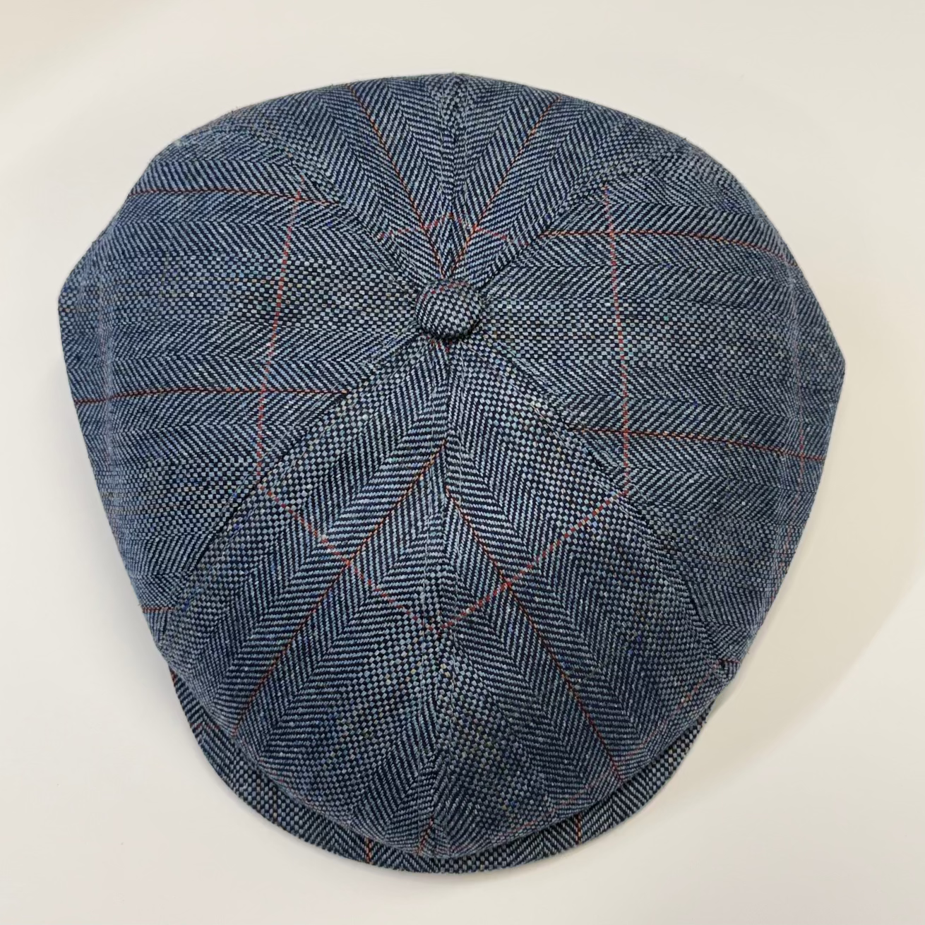 Blue checkered flat cap on a light beige background