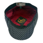 A vintage patterned flat cap with a dark gray and black geometric design, a dark green interior band, and a burgundy red inner lining. The front crown features a black patch with gold embroidered 'Laffy Hatters' logo and deer antlers.