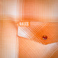Close-up of an orange and cream plaid button-down shirt pocket with a visible Hales brand tab and a snap button closure.