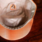 Close-up of the inside of a plaid orange and beige cap resting on a dark wooden surface, showing the interior lining and a sewn-in label.