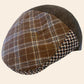 A brown plaid flat cap with a dark brown woven side panel and a textured brown fabric crown, resting on a crumpled white surface.