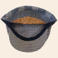 A vintage-style flat cap with a blue and beige houndstooth patterned brim, a patterned blue and gray crown, a black fabric trim, and a natural cork lining.