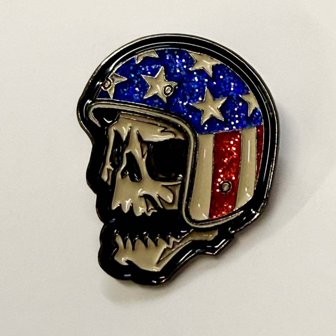Pin with a design of a person wearing a helmet with an American flag pattern on a white background