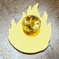 A gold enamel pin shaped like a flame, showing the back side with a textured grid pattern and a shiny gold pin clasp, placed on a dark wood surface.