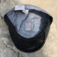 A black mesh-back cap with a gray patterned inner lining, laid flat on a textured stone surface. The brand name 'Graver' is visible on the inner label.