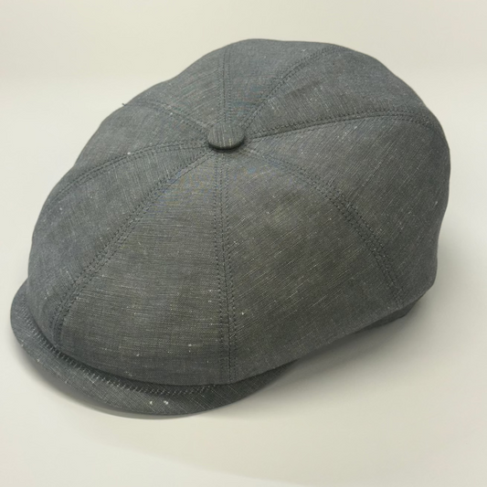 A dark gray textured flat cap with a button on top, photographed on a light neutral background.