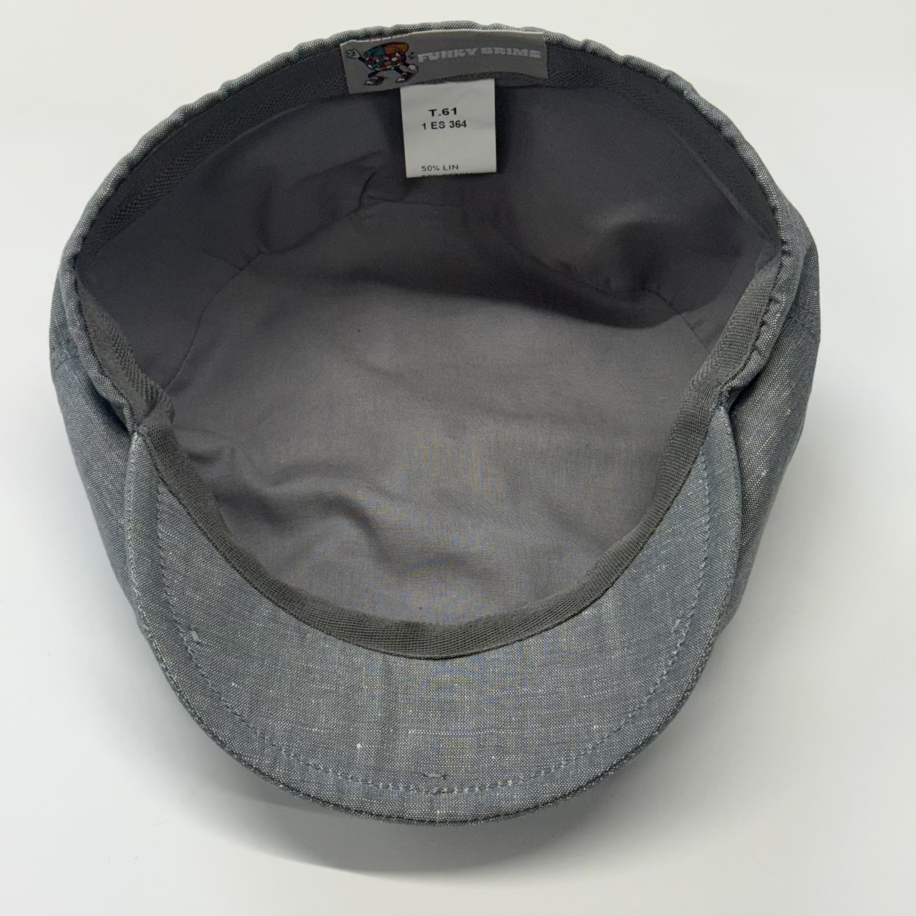Gray textured fabric flat cap shown from the inside, with a visible interior label reading 'Perry White' and size 'T41 12-34'.