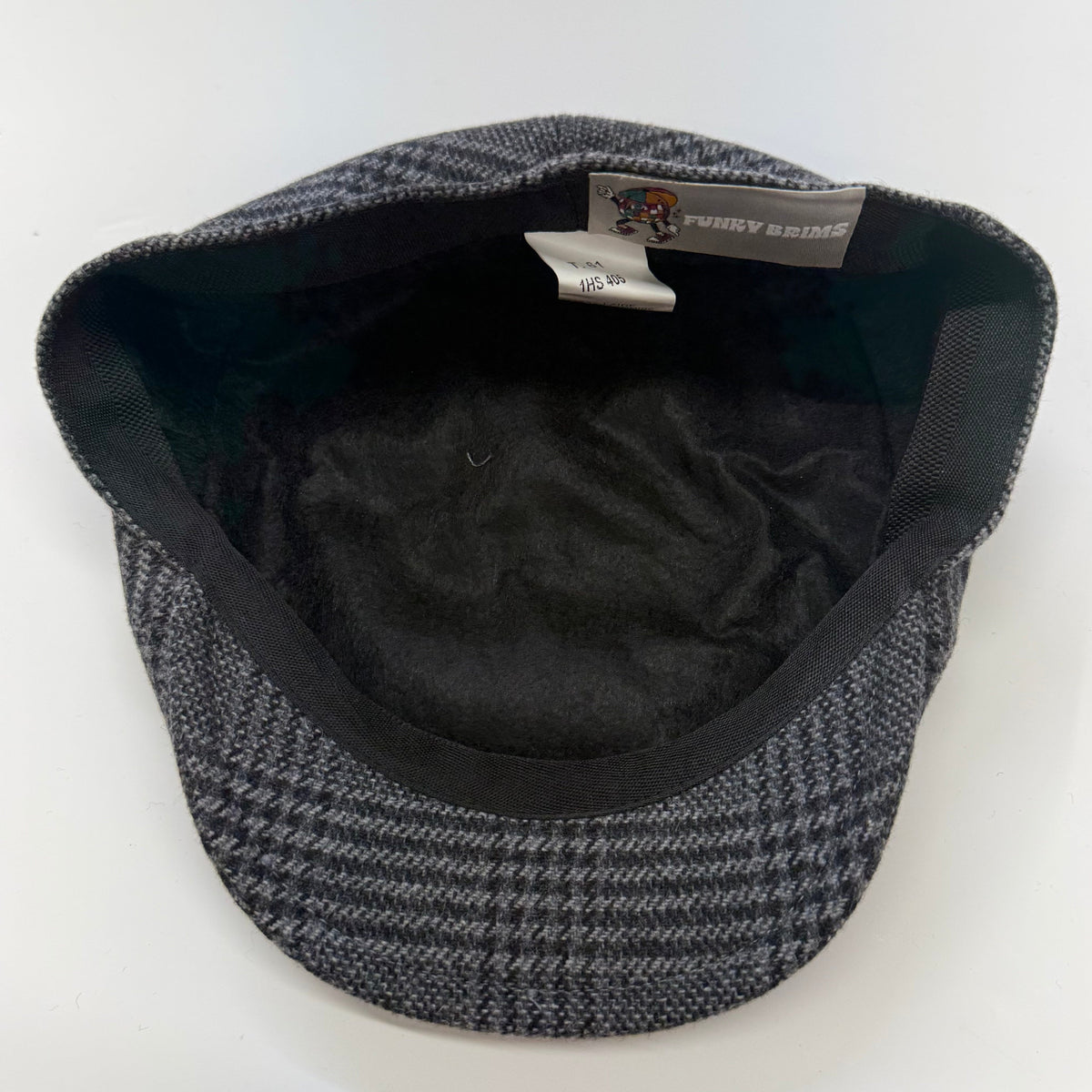 A vintage-style flat cap with a black and gray houndstooth pattern, featuring a black plush fleece lining and a visible 'Every Day' brand tag inside the crown.