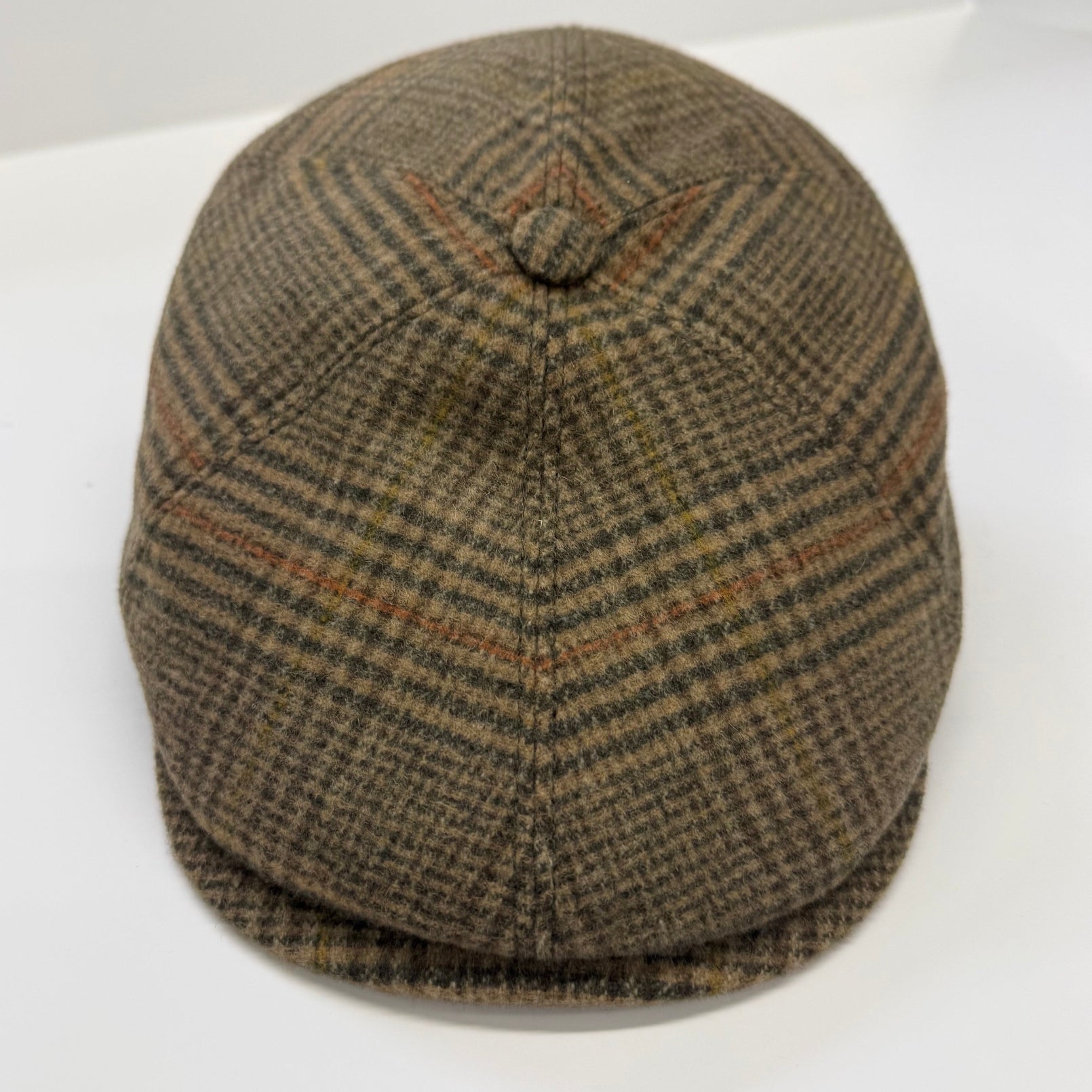 A classic flat cap in a brown and beige houndstooth pattern with subtle orange-brown stripes, photographed on a clean white background.