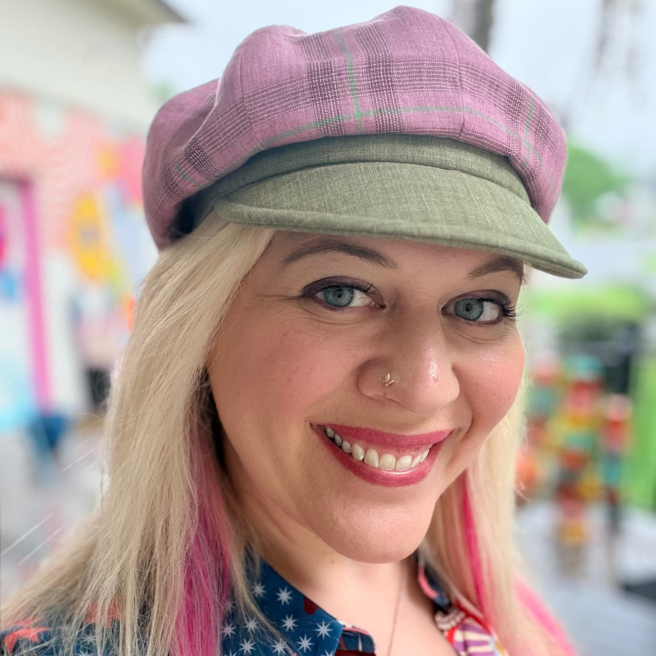 Woman wearing a colorful shirt and two hats with a blurred background