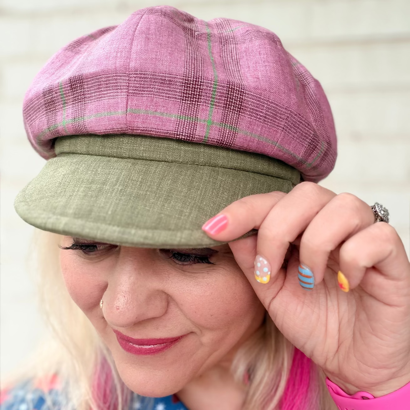 Woman wearing a colorful shirt and two hats with a blurred background
