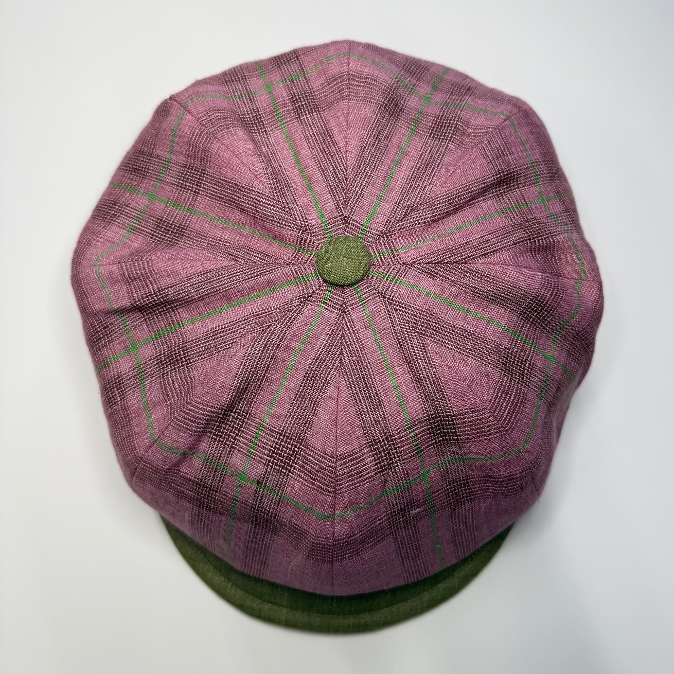 Purple checkered cap with a green button on a white background
