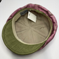 Green and pink checkered flat cap with brand label on a white background