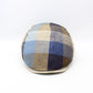 A round, low-profile cap with a multi-colored plaid pattern in shades of blue, beige, brown, and gray, photographed against a plain white background.