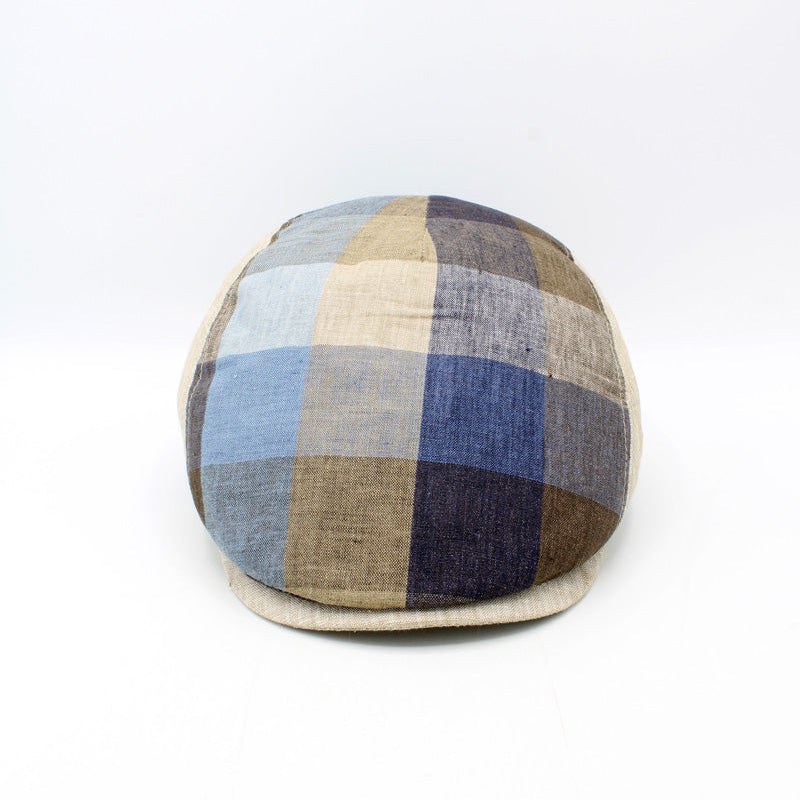 A round, low-profile cap with a multi-colored plaid pattern in shades of blue, beige, brown, and gray, photographed against a plain white background.