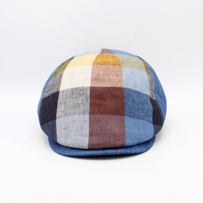 A structured flat cap with a multi-colored plaid pattern featuring shades of blue, beige, brown, and yellow, set against a plain white background.