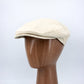 Beige cap on a wooden mannequin head against a white background