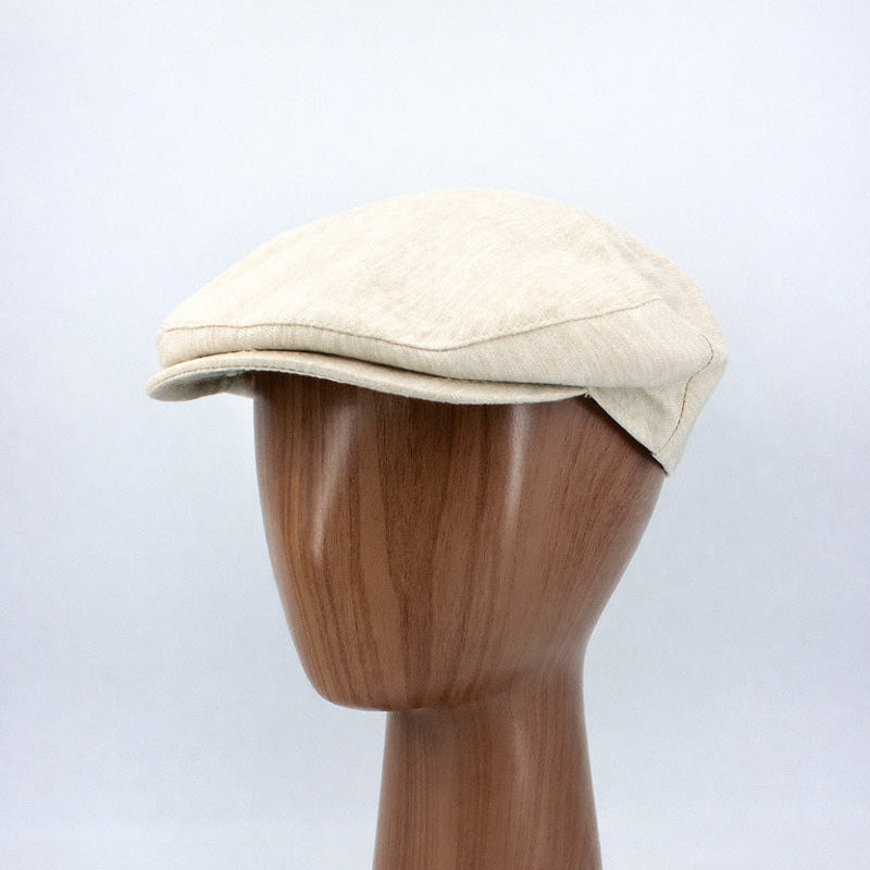 Beige cap on a wooden mannequin head against a white background