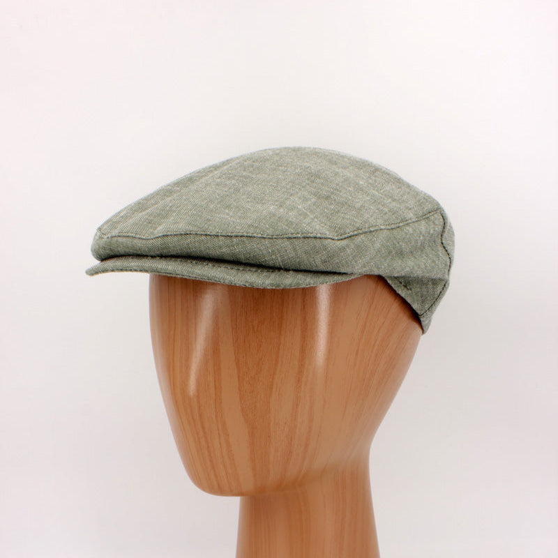 Green flat cap on a wooden mannequin head against a white background