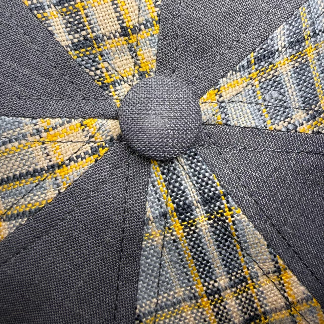 Close-up of a gray and yellow checkered fabric with a button detail