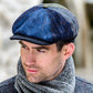 Man wearing a blue and green checkered cap and gray scarf outdoors.