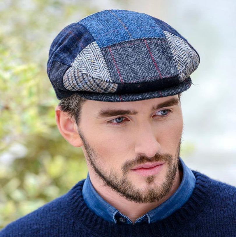 Man wearing a patchwork cap and blue sweater outdoors