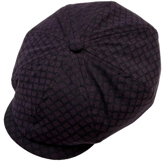 A dark purple and black patterned newsboy cap photographed on a plain light background.