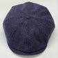 A dark purple herringbone pattern flat cap, also known as a newsboy cap, photographed from a top-down angle on a light gray background.